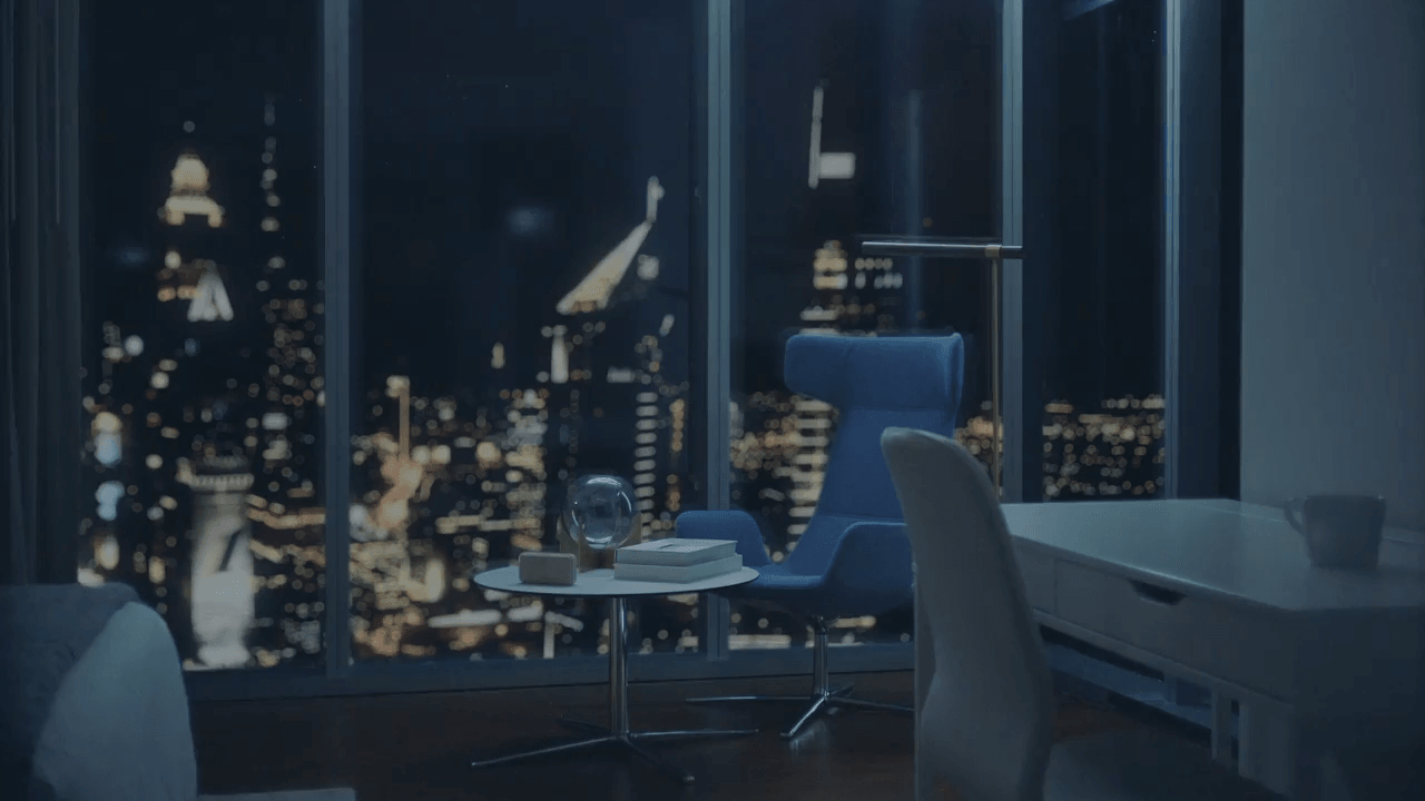 Hotel room with floor-to-ceiling windows and view of city skyline at night.