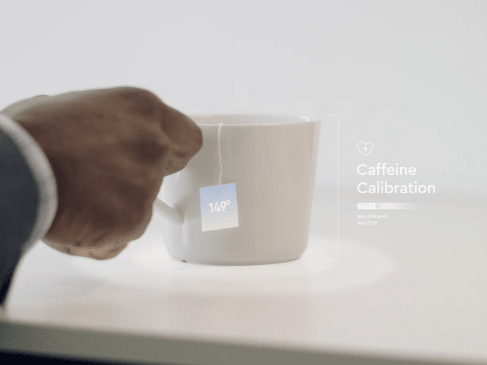 Man’s hand picking up a tea cup. Caption reads Caffeine Calibration.